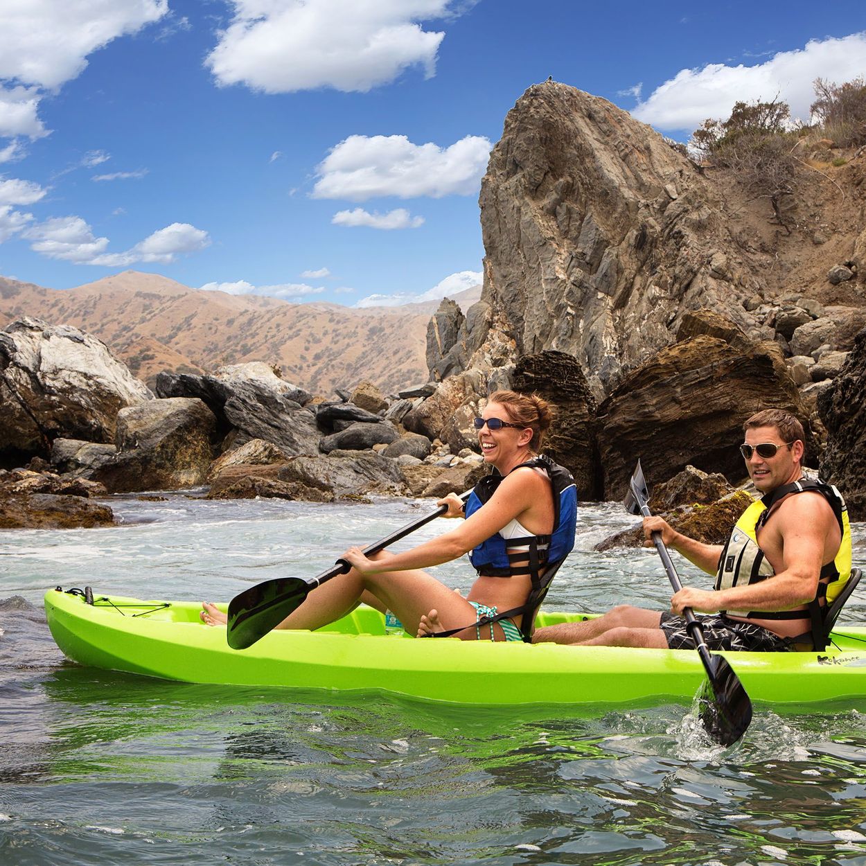 Lifestyle Side view of couple tandem kayaking by rocks showing how the kayak looks with two on the kayak.