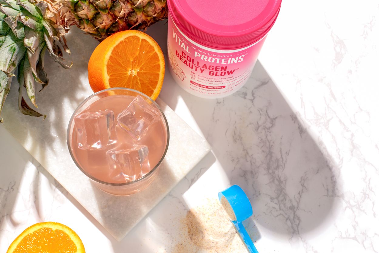 Glass of juice next to fruits and product bottle