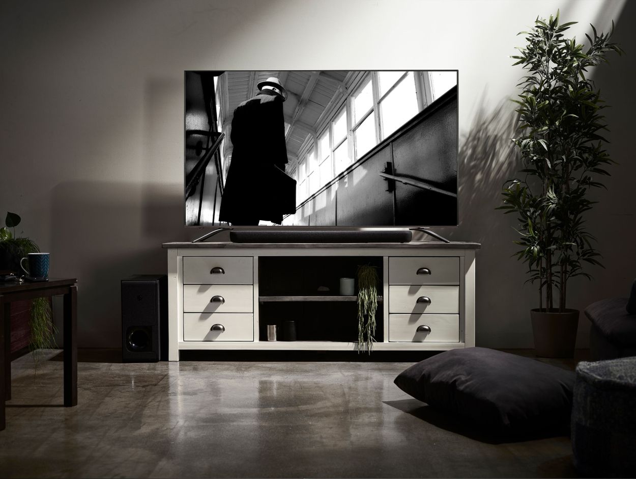 Sound bar on credenza in front of TV with movie on screen