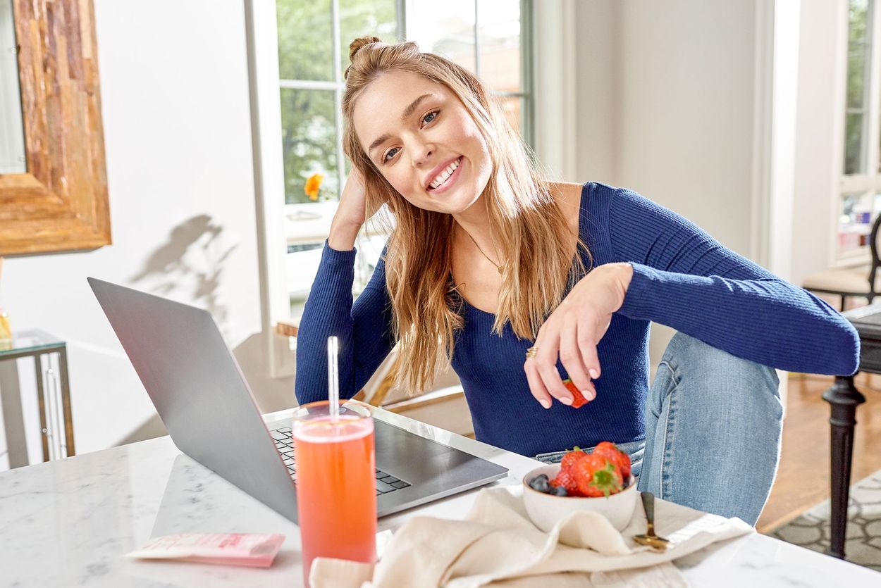 Girl sitting with laptop and collagen drink next to it