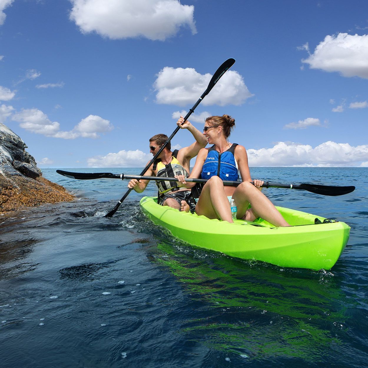 Lifestyle image of 3/4 view of a couple kayaking on the ocean